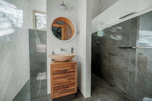 A modern bathroom with a wooden vanity, a round mirror, and a large sink. - Orchard Cottage—Romantic Bushland Wellness Retreat (Yallingup Siding)