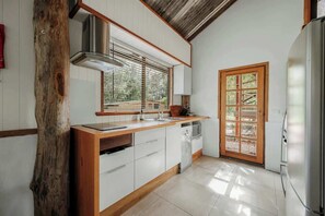 Una cocina con armarios blancos, encimera de madera, campana de acero inoxidable y una ventana con persianas.