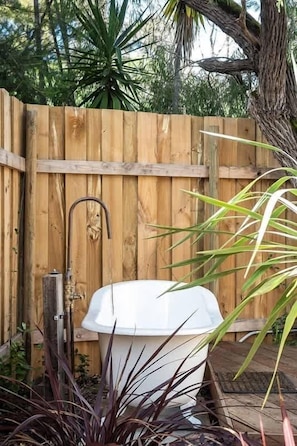 Una valla de madera, una bañera blanca y algunas plantas.