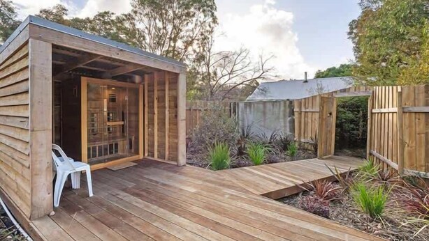 A wooden deck with a covered seating area, a small garden, and a wooden fence. - Orchard Cottage—Romantic Bushland Wellness Retreat (Yallingup Siding)