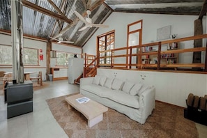 Una habitación amplia con techo alto, un sofá, una mesita de café, una estantería y una escalera.