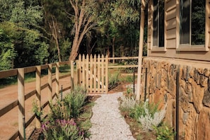 A pathway leading to a house with a wooden fence and a stone wall.