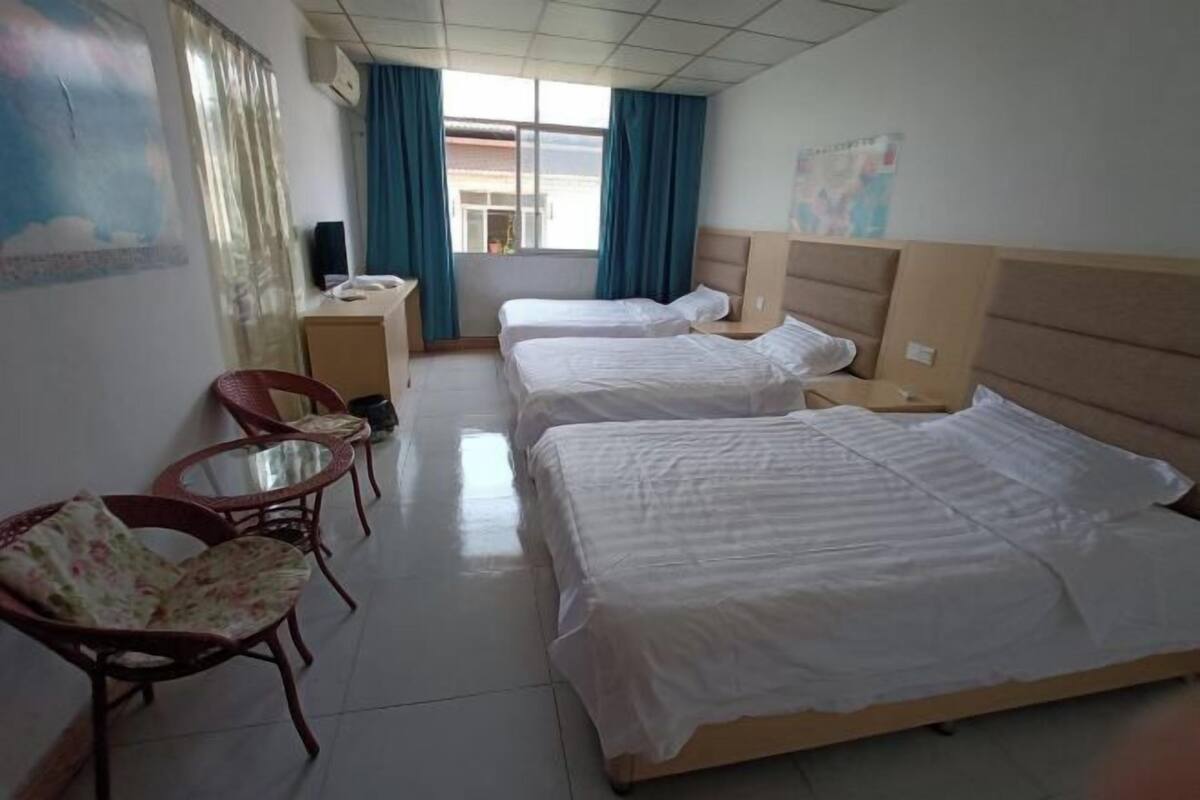A hotel room with two beds, a desk, a chair, and a window with curtains.