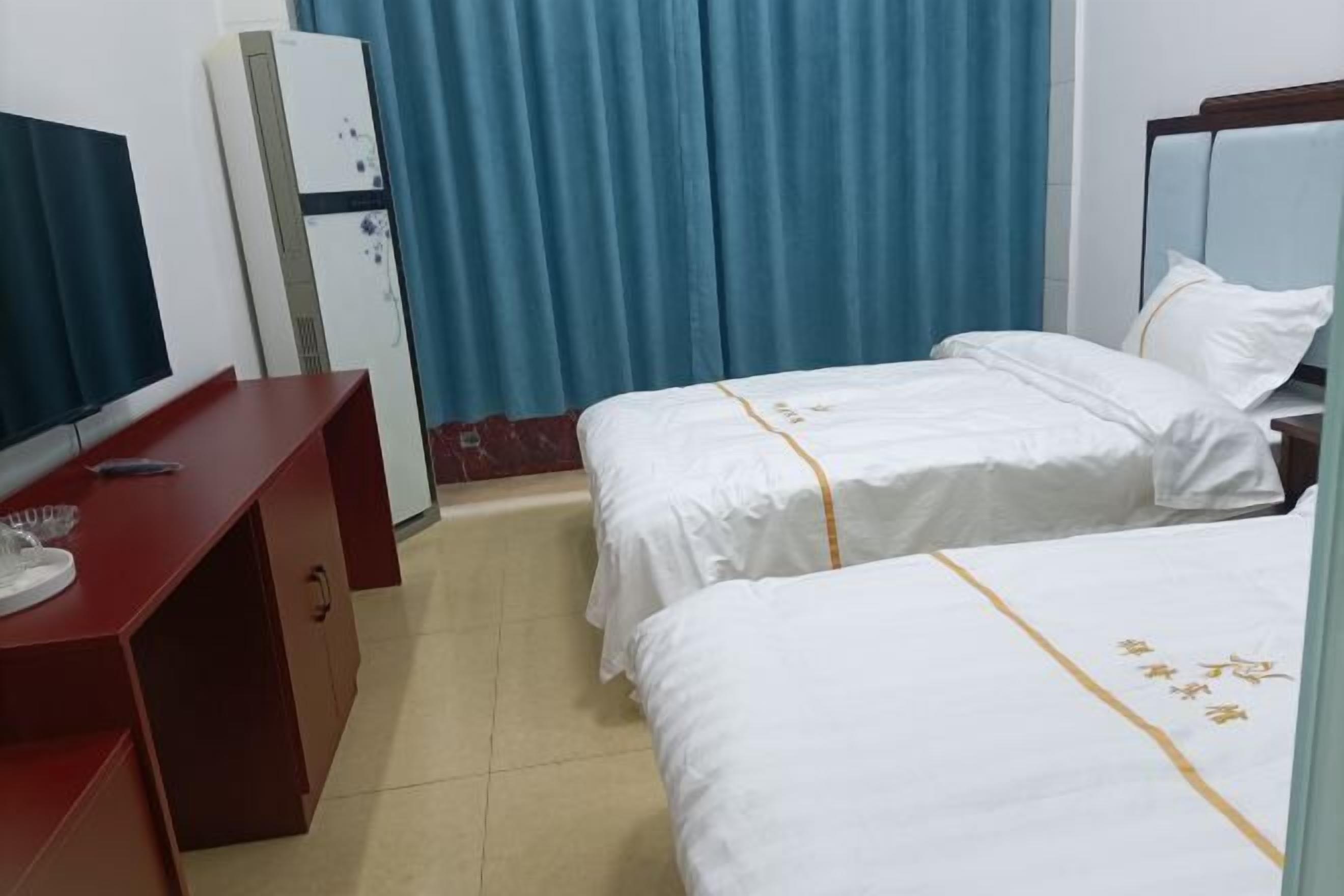 Una habitación de hotel con dos camas individuales, un escritorio con televisor y un armario.