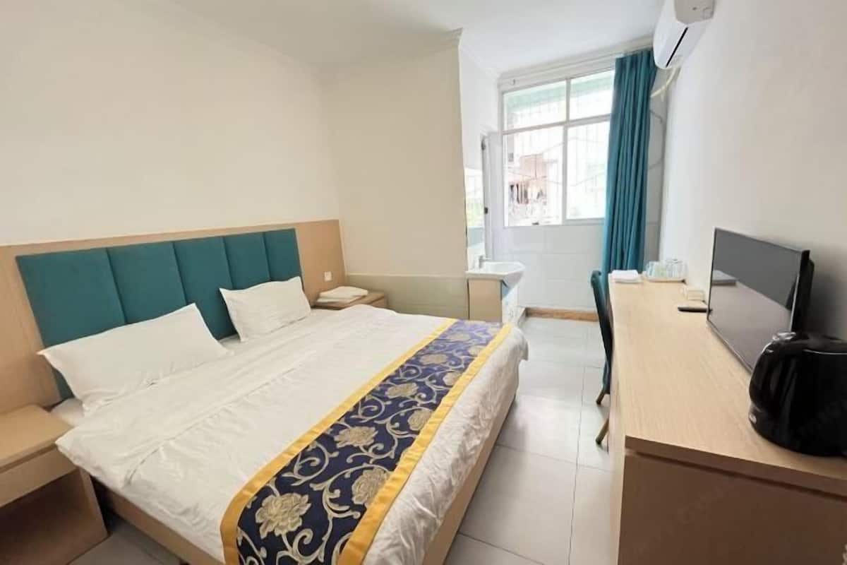 A hotel room with a bed, a desk, a television, and a window.