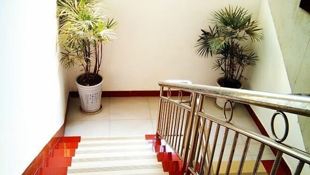 A staircase with red steps and a metal railing, flanked by potted plants. - Xiang Long Hotel (Guanghan)