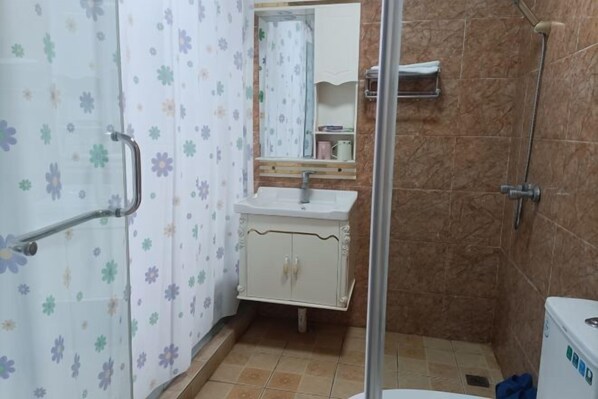 A bathroom with a shower, a sink, and a mirror. - Xiang Long Hotel (Guanghan)
