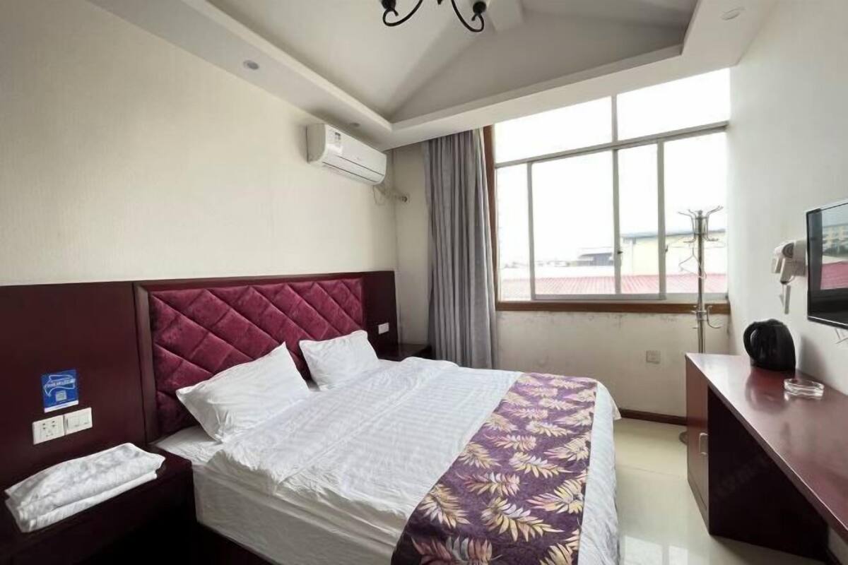 A hotel room with a bed, a desk, a TV, and a window with curtains.