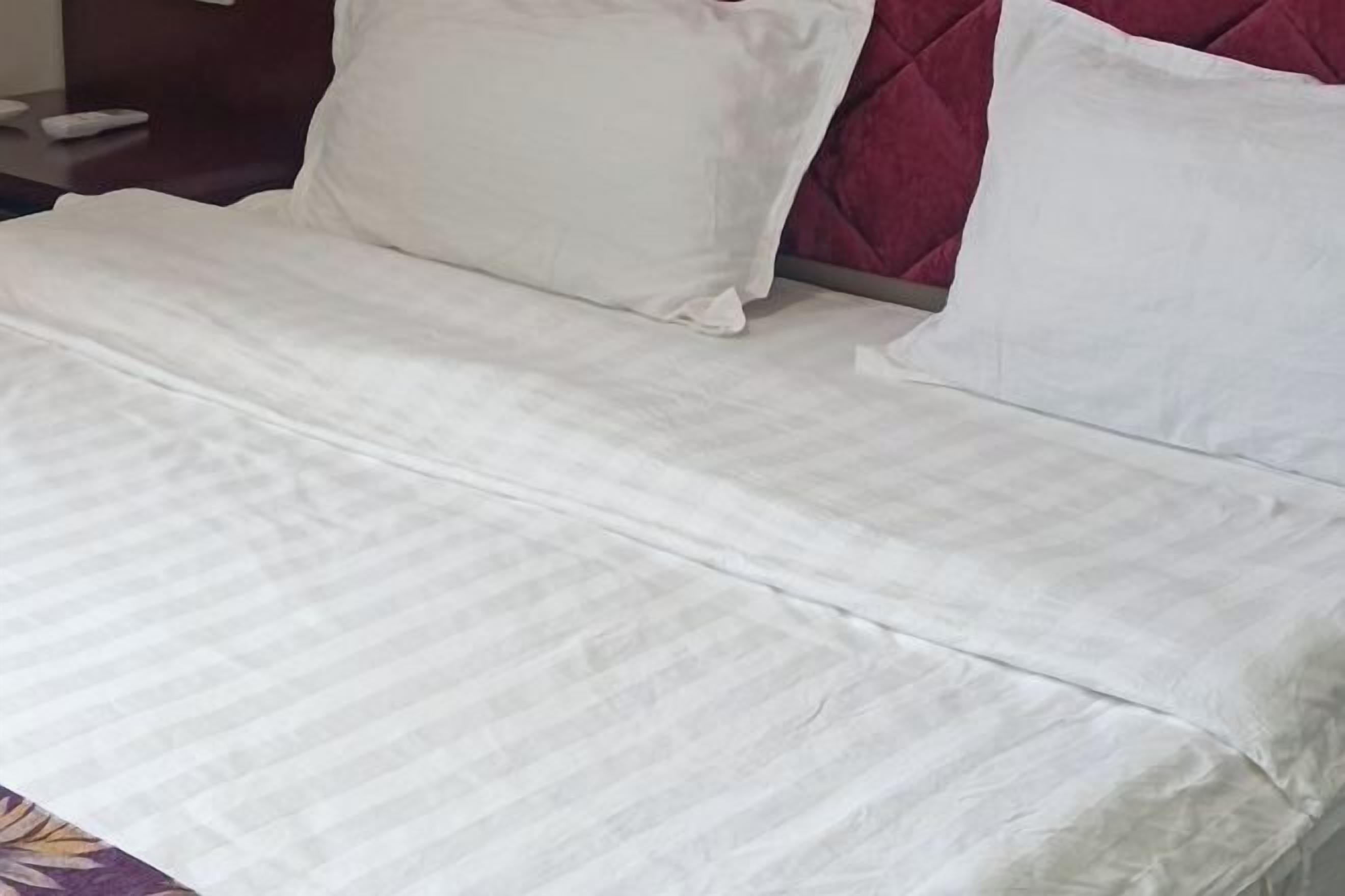 A bed with white bedding and a red headboard.