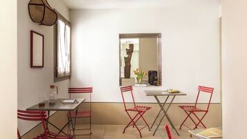 A small dining area with a table, four red chairs, a vase with flowers, and a mirror on the wall.