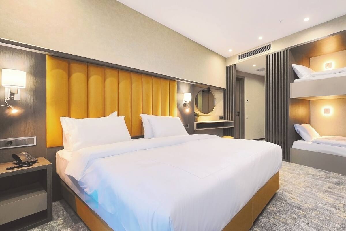 Ein Hotelzimmer mit einem großen Bett, einem Nachttisch mit Telefon, einem Spiegel und einer Wandlampe.