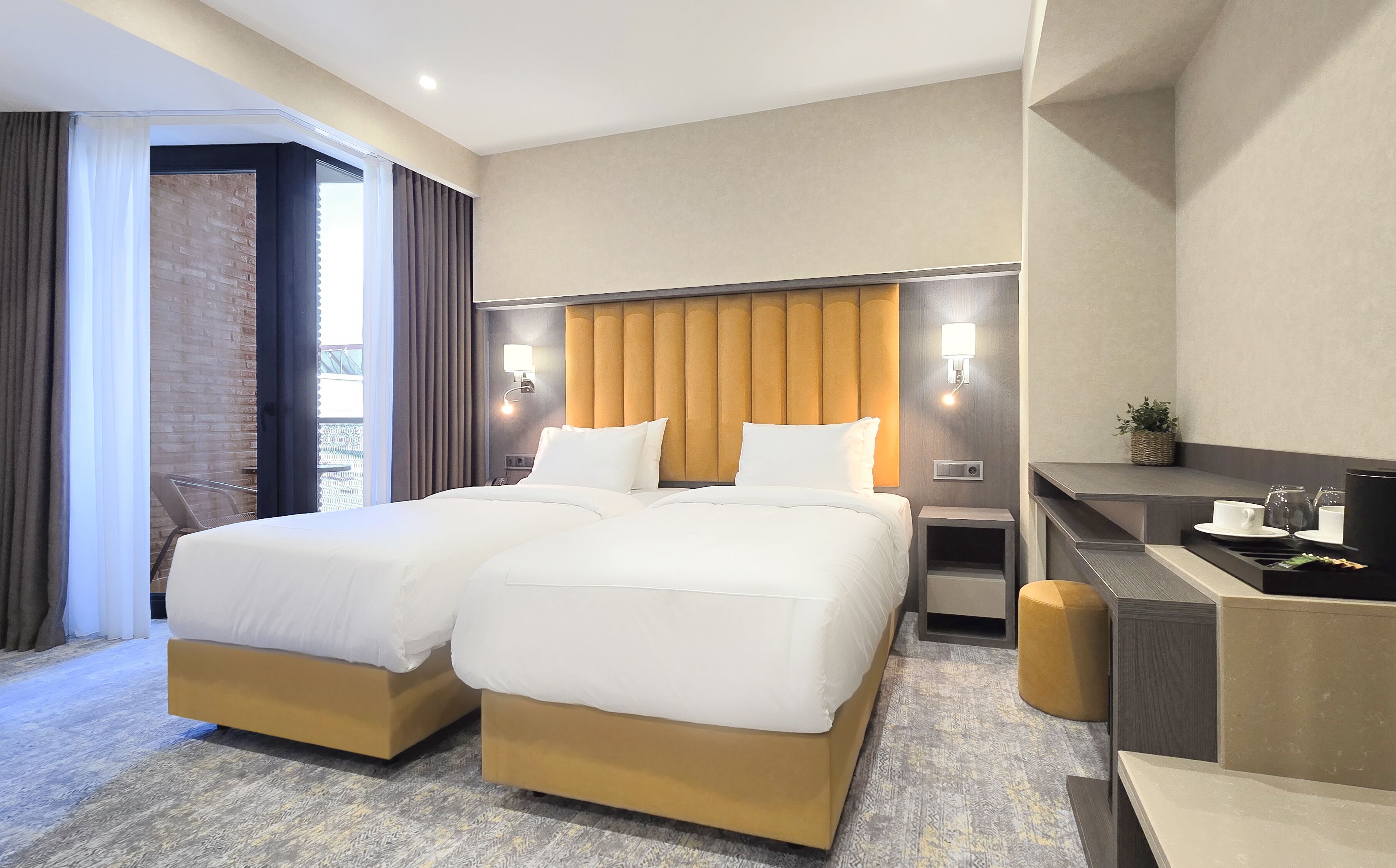 Une chambre d’hôtel avec deux lits, un bureau et un petit coin salon.