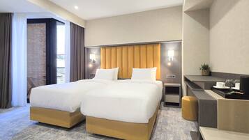 Une chambre d’hôtel avec deux lits, un bureau et un petit coin salon.