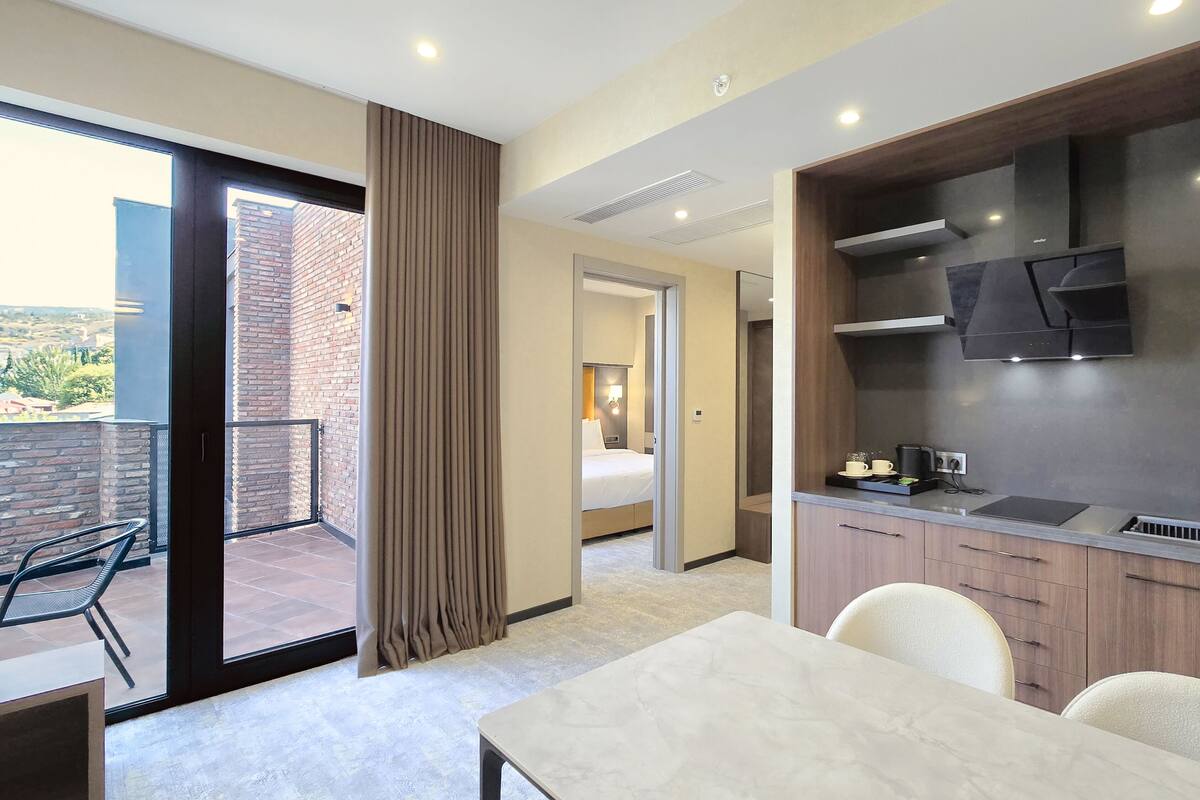 Ein modernes Hotelzimmer mit Balkon, Essbereich und Küchenzeile.