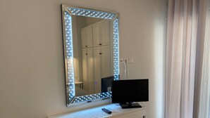 A room with a large mirror with LED lights, a desk with a computer monitor, and a chair. - Angel's Apartment Volos (Volos)