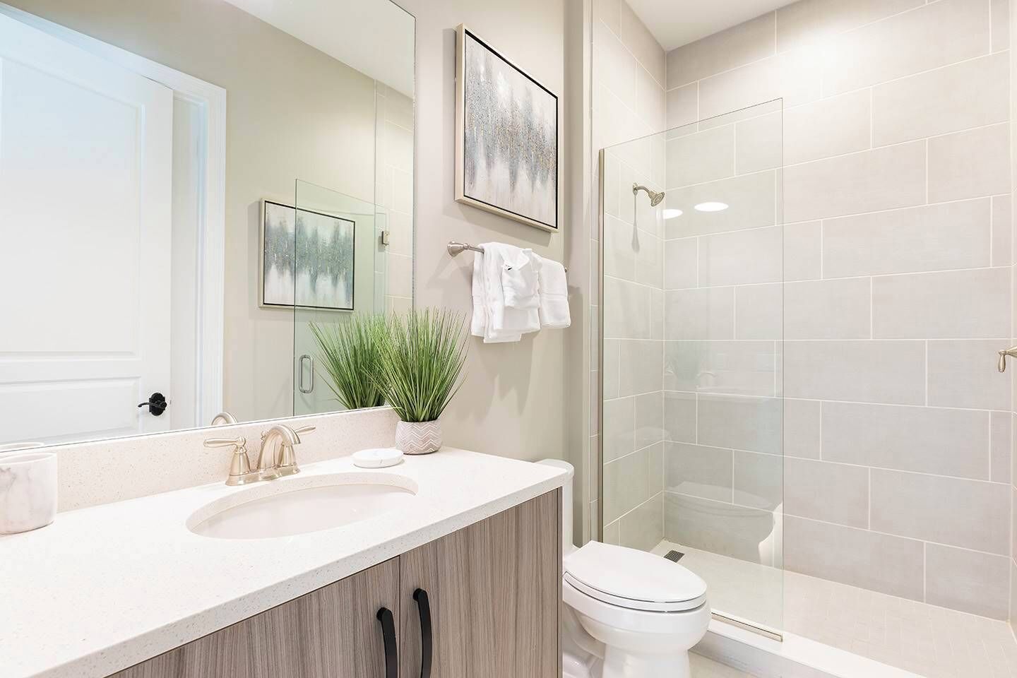 Un bagno moderno con uno specchio grande, un lavabo, un water e una cabina doccia in vetro.