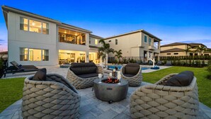 A modern two-story house with a patio area featuring wicker furniture and a fire pit. - Bear's Den At Reunion Resort-TB024 (Kissimmee)