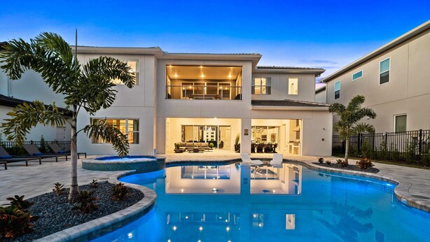 A modern two-story house with a swimming pool, outdoor seating, and a well-lit interior. - Bear's Den At Reunion Resort-TB024 (Kissimmee)