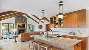 A modern kitchen with a large island, wooden cabinets, and pendant lighting. - The Hideout: Luxe Escape w/ Sauna & Hot Tub | Birchwood Golf & CC (Harbor Springs)