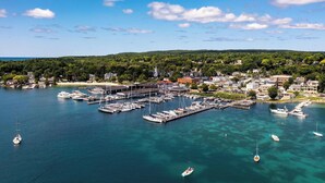 A marina with multiple docks and boats, surrounded by residential buildings and a hilly landscape. - The Hideout: Luxe Escape w/ Sauna & Hot Tub | Birchwood Golf & CC (Harbor Springs)
