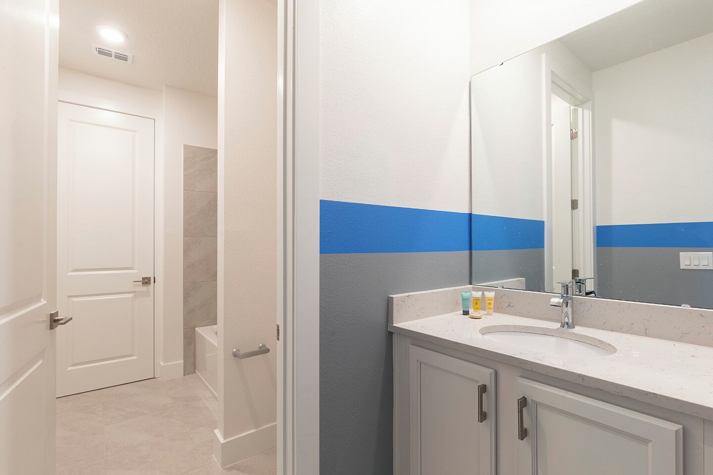 Un baño con un lavamanos blanco, un espejo y una puerta que da a la zona de la ducha.