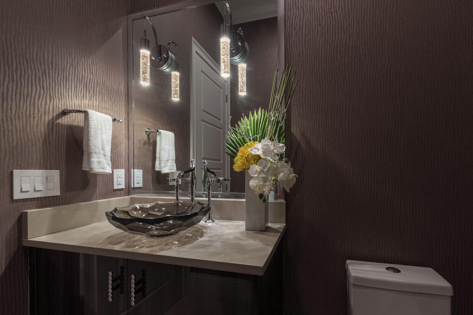 A modern bathroom with a glass bowl sink, a mirror, and a toilet.