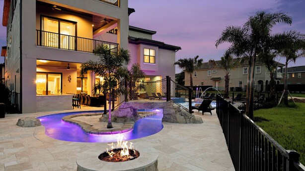 A multi-story hotel with a pool area featuring a fire pit and a water feature.