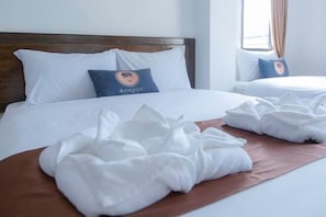 Habitación de hotel con una cama grande, dos almohadas, una colcha marrón y una ventana con cortinas.