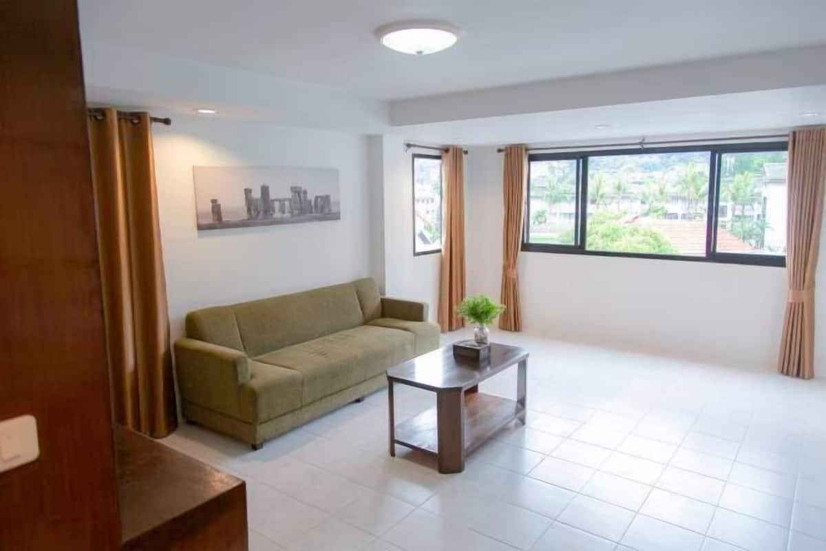 A living room with a sofa, a coffee table, and a window with curtains.