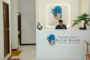 Ein Empfangstisch mit dem Logo von RoomQuest Phuket Kalim Beach Premium Collection.