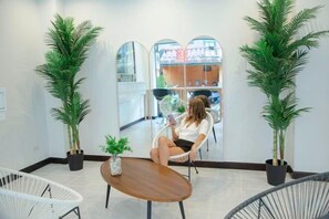 A room with a large mirror, two potted plants, a round wooden table, and a white chair. - RoomQuest the Beach Kalim Patong (Phuket)
