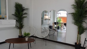 Un intérieur moderne comprenant un coin repas, des chaises blanches, une table en bois et des plantes en pot.
