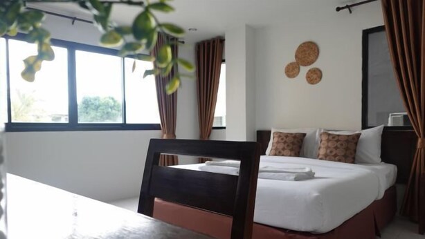 A hotel room with a bed, a desk, and a window with curtains. - RoomQuest the Beach Kalim Patong (Phuket)