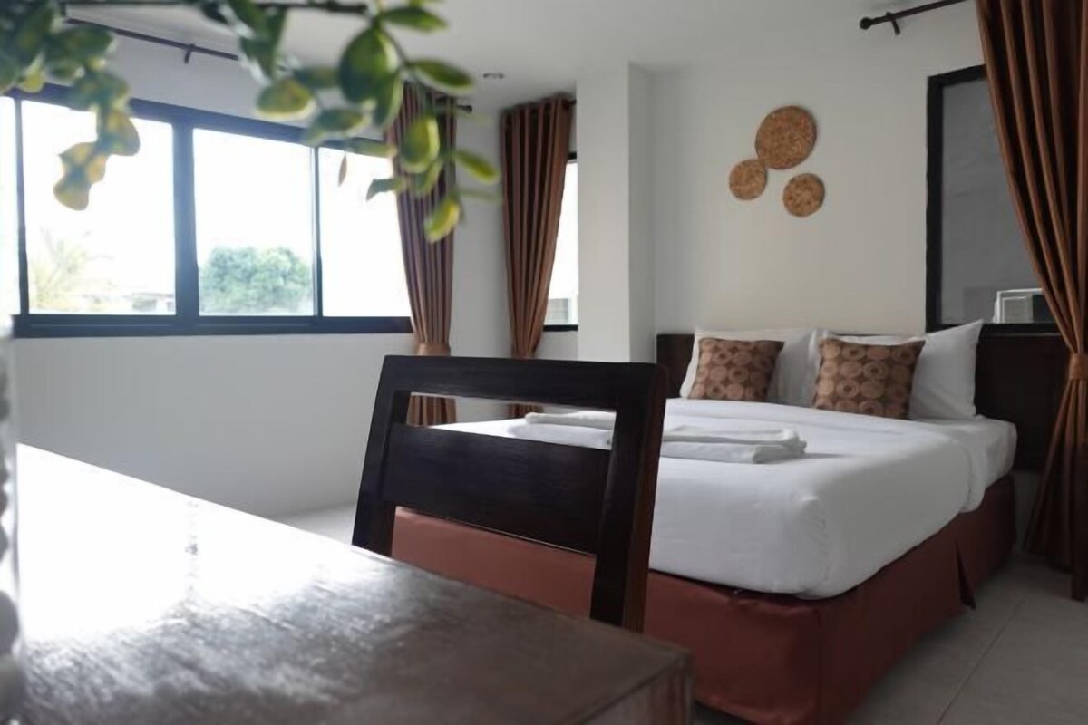 A hotel room with a bed, a desk, and a window with curtains.