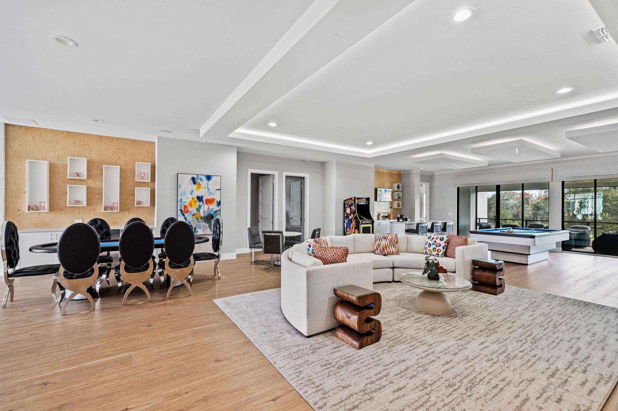 A spacious living room with a large sectional sofa, a coffee table, and a dining area with a round table and chairs.