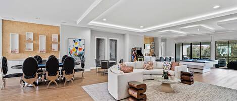 A spacious living room with a large sectional sofa, a coffee table, and a dining area with a round table and chairs.