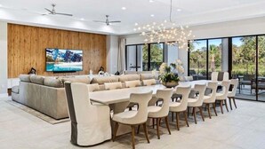Un espace repas moderne comprenant une grande table et des chaises, un canapé et un téléviseur.