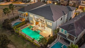 Une maison à deux étages dotée d’un grand jardin comprenant une piscine, un espace salon extérieur et une terrasse couverte.