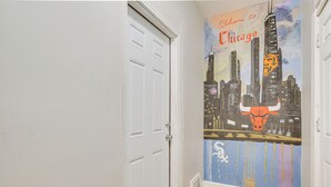 Ein Flur mit Wandgemälde der Skyline von Chicago, einer weißen Tür und Holzböden.