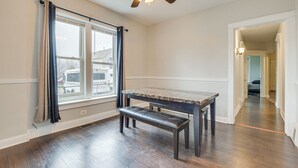 Ein Zimmer mit Esstisch, Bank und Deckenventilator.