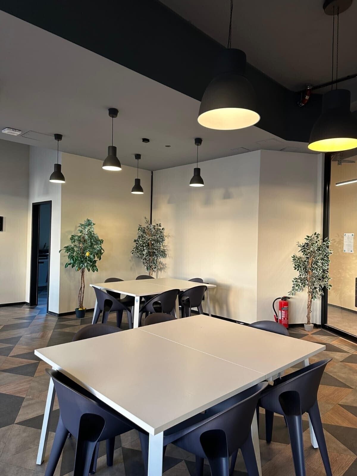 A modern conference room with a large table, black chairs, and pendant lighting.