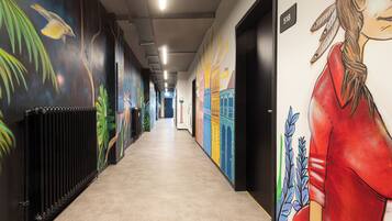 Un pasillo con murales coloridos en las paredes, un radiador a la izquierda y una puerta con el número 518 a la derecha.