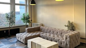 A modern living room with a sectional sofa, pendant lighting, and a geometric patterned floor. - Coffee Inn Hostel Berlin (Berlin)