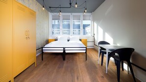 A bedroom with a bed, yellow wardrobe, and a window with a view of buildings. - Coffee Inn Hostel Berlin (Berlin)
