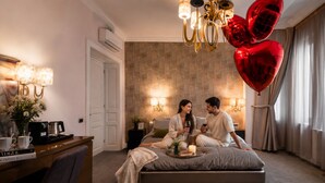 A bedroom with a bed, bedside lamps, a nightstand, a coffee maker, and a vase with flowers. - Highline Downtown Aparthotel (Bucharest)