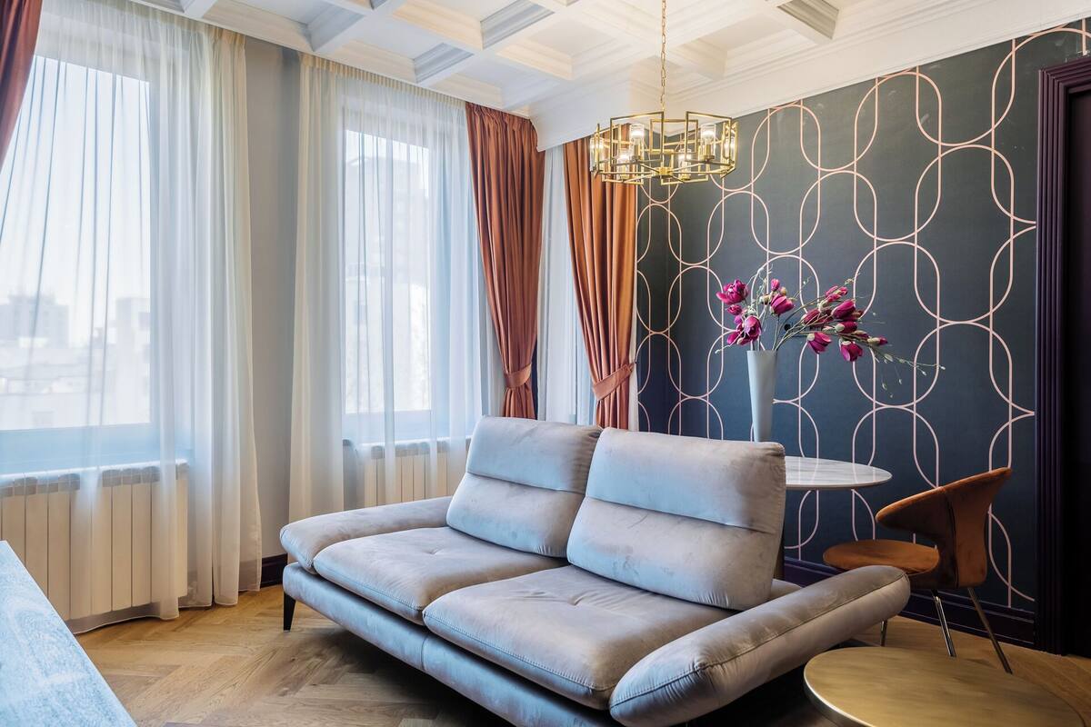 A modern living room with a grey sofa, a round coffee table, and a decorative vase with flowers.