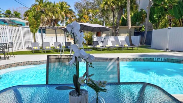 A pool area with lounge chairs and a flower arrangement. - Apartment for 4 guests (Sarasota)