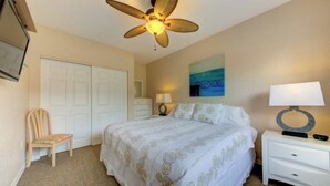 A bedroom with a bed, a ceiling fan, a chair, a dresser, a nightstand, and a painting on the wall. - Apartment for 4 guests (Sarasota)