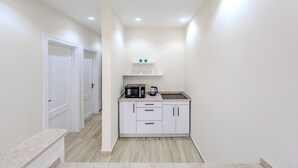 A compact kitchen with white cabinets, a microwave, and a kettle. - Styling 5 BR Duplex Apartment (First 6th of October)