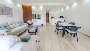 A modern living room with a sofa, coffee table, and dining area with chairs and a table. - Styling 5 BR Duplex Apartment (First 6th of October)